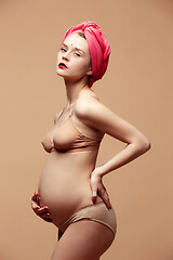 Image showing Young beautiful pregnant woman posing on brown background