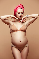 Image showing Young beautiful pregnant woman posing on brown background