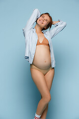 Image showing Young beautiful pregnant woman posing on blue background