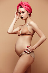 Image showing Young beautiful pregnant woman posing on brown background