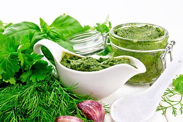 Image showing Sauce of spicy greens in gravy boat and jar on light board