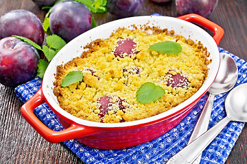 Image showing Crumble with plum in brazier on dark board