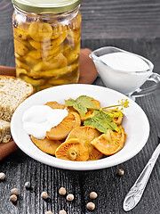 Image showing Mushrooms salted with sour cream in plate on black wooden board