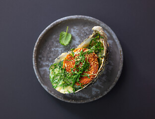 Image showing baked oyster with toasted bread and greens on grey plate, top vi