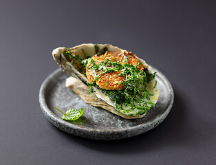 Image showing baked oyster with toasted bread and greens on grey plate