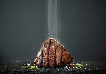 Image showing the salt is poured onto freshly grilled steak