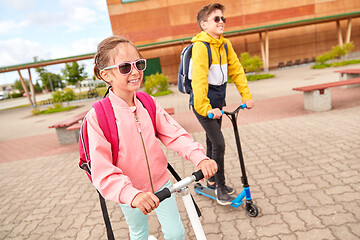 Image showing happy school children with backpacks and scooters