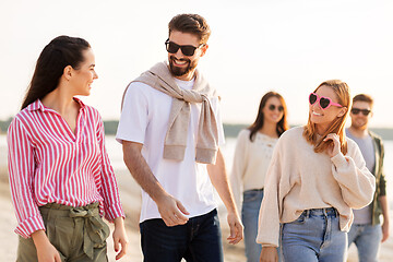 Image showing happy friends walking along summer beach