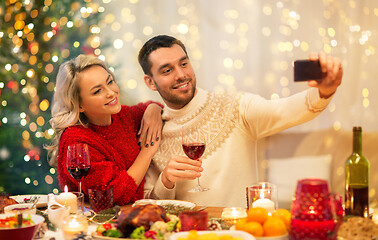 Image showing happy couple taking selfie at christmas dinner