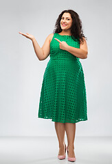 Image showing happy woman in green pointing fingers at something