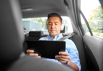 Image showing passenger with headphones using tablet pc in car