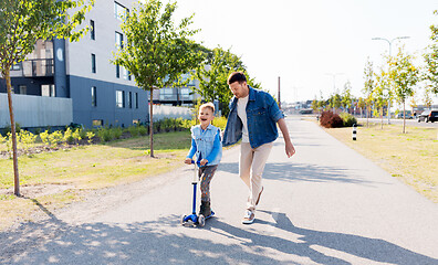 Image showing happy father and little son riding scooter in city