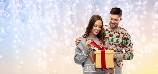 Image showing happy couple in christmas sweaters with gift box