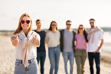 Image showing woman with friends on beach showing thumbs up