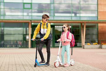 Image showing happy school children with backpacks and scooters