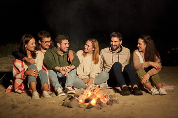 Image showing group of friends sitting at camp fire on beach