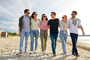 Image showing happy friends walking along summer beach