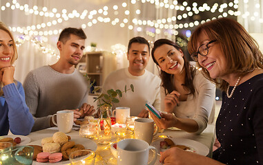 Image showing happy family with smartphone at tea party at home