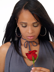 Image showing Young black woman looking down at red rose