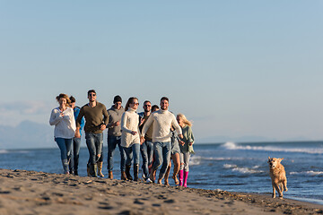 Image showing Group of friends running on beach during autumn day