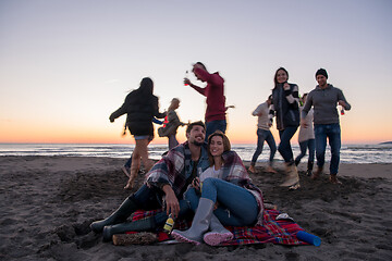 Image showing Couple enjoying with friends at sunset on the beach