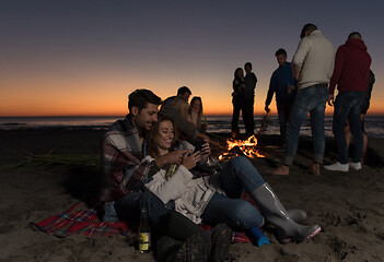 Image showing Couple enjoying bonfire with friends on beach