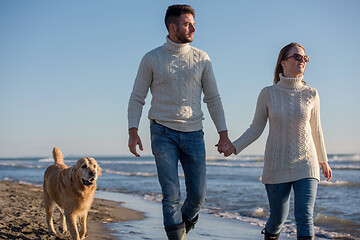 Image showing couple with dog having fun on beach on autmun day