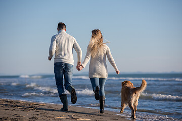 Image showing couple with dog having fun on beach on autmun day