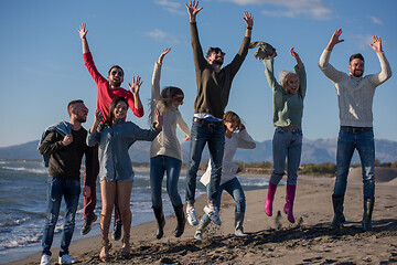 Image showing young friends jumping together at autumn beach