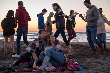 Image showing Couple enjoying with friends at sunset on the beach