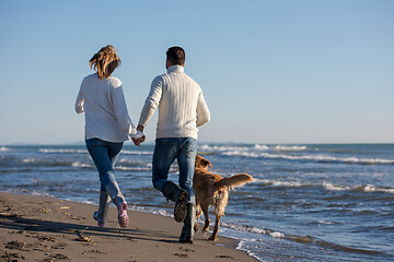 Image showing couple with dog having fun on beach on autmun day