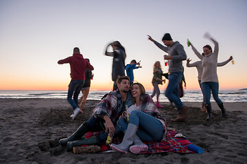 Image showing Couple enjoying with friends at sunset on the beach