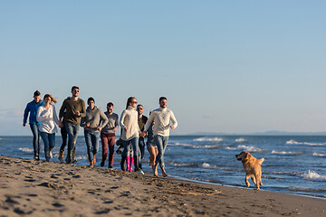 Image showing Group of friends running on beach during autumn day