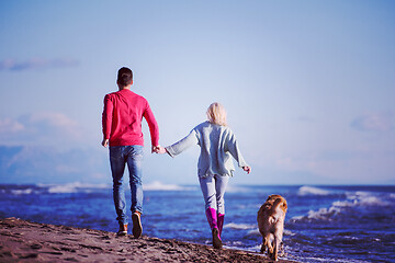 Image showing couple with dog having fun on beach on autmun day