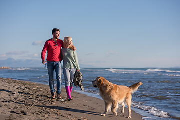 Image showing couple with dog having fun on beach on autmun day