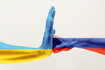 Image showing Two hands. Flag of Russian Federation. Flag of Ukraine.