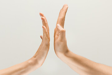 Image showing Male and female hands demonstrating a gesture of getting touch isolated on gray background