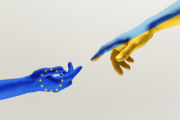 Image showing Two hands. Flag of the European Union. Flag of Ukraine.