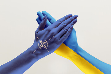 Image showing Male and female hands colored in flags of Ukraine and NATO