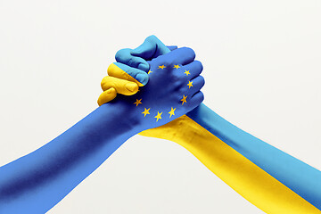 Image showing Two hands. Flag of the European Union. Flag of Ukraine.