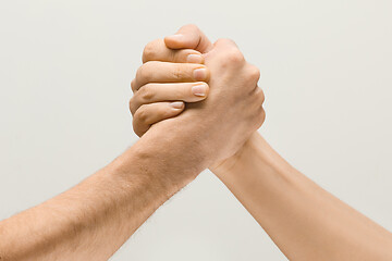 Image showing Two male hands competion in arm wrestling isolated on grey studio background