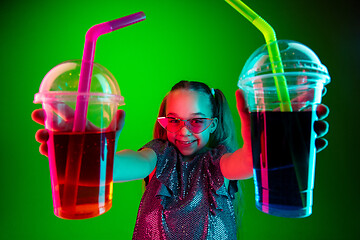 Image showing The happy teen girl standing and smiling against green lights background.