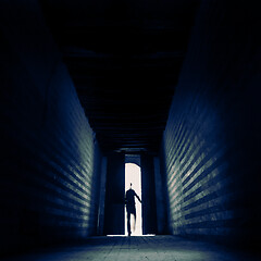 Image showing Entering the unknown. Person\'s silhouette entering trough doorway to dark backlit hall. Entering the unknown.