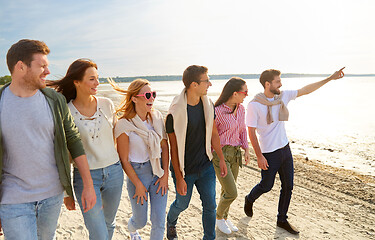 Image showing happy friends walking along summer beach