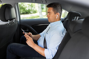 Image showing passenger with earphones and cellphone in taxi car