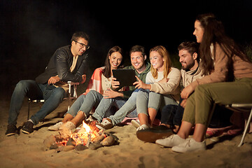 Image showing friends with tablet pc at fire on beach at night