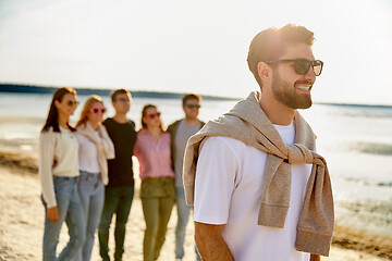 Image showing happy man with friends on beach in summer