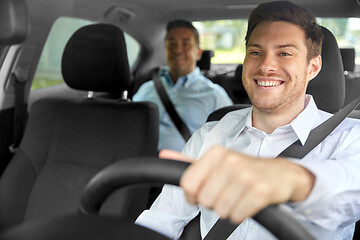 Image showing male taxi driver driving car with passenger