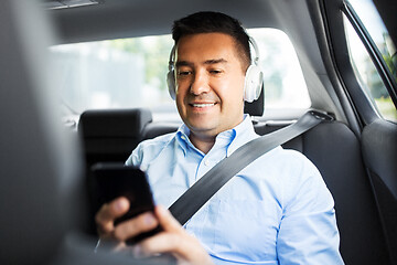 Image showing passenger with headphones using smartphone in car