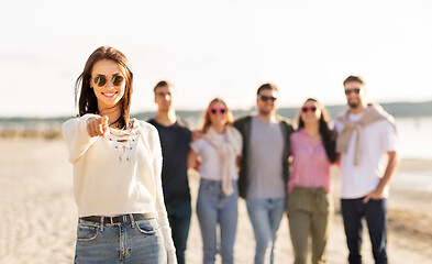 Image showing happy woman with friends on beach pointing to you